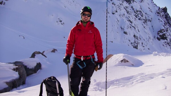 Guide explaining rescue equipment next to a probe while holding an ice axe